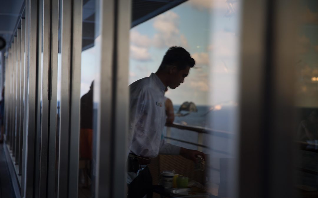 Un trabajador de Indonesia recoge platos sucios en una cubierta después de un almuerzo. Los trabajadores de crucero tienen contratos de hasta nueve meses durante los cuales trabajan más de 70 horas a la semana, sin vacaciones ni días de descanso. Almudena Toral/Univision