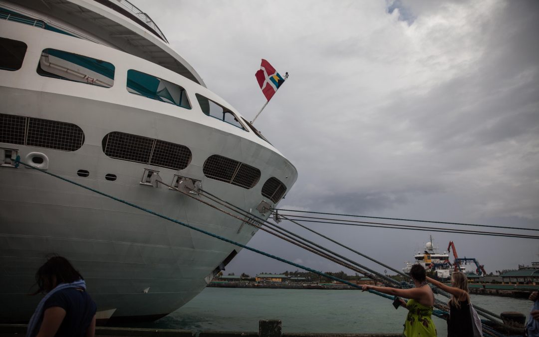 Pasajeros regresan a un crucero antes del atardecer después de un día en Nassau, Bahamas. Es habitual que la bandera de un crucero sea de un país, su dueño de otro y la empresa que lo opera de un tercero. Almudena Toral/Univision