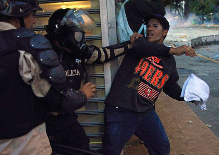 A member of the National Police struggles with an anti-government student taking part in a protest, in Caracas on February 15, 2014.
